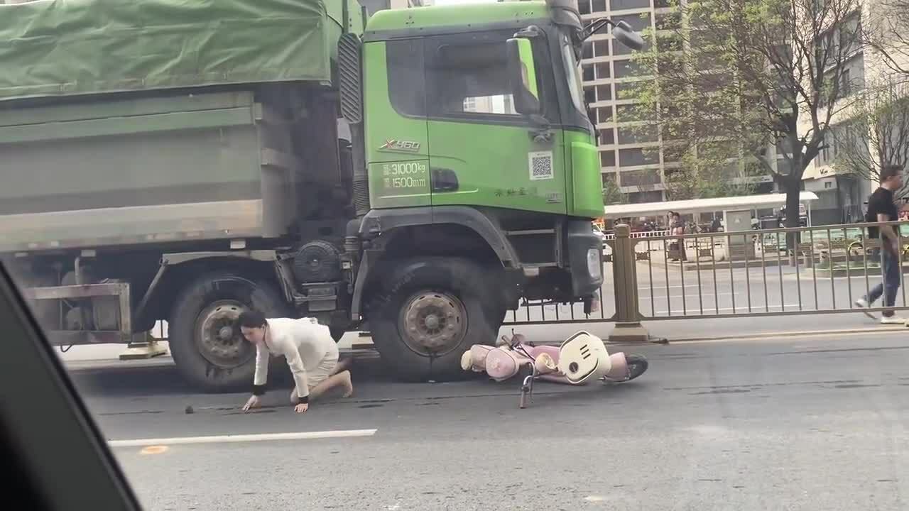 Người phụ nữ đi xe máy chui ra từ gầm xe ben