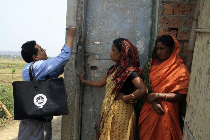Nhân viên điều tra dân số (trái) đánh dấu một ngôi nhà ở thành phố Guwahati, bang Assam, sau khi thu thập thông tin hồi tháng 4/2010. Ảnh: Reuters